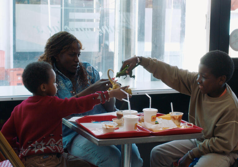 A mother sits in a diner with her two young sons