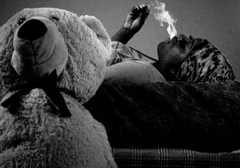 A woman looks at a teddy bear in a black and white photograph