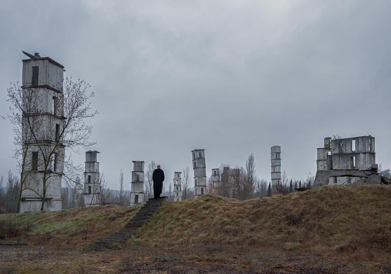 Anselm Kiefer walks in a misty landscape amongst his large, industrial sculptures.