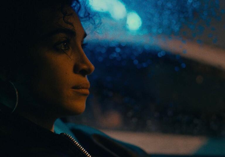 A woman sits in her car looking pensive