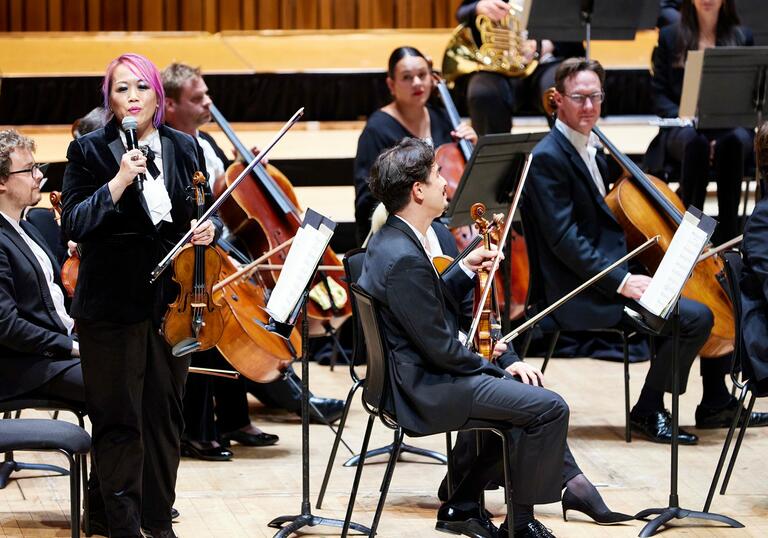 LSO Violinist Maxine Kwok introducing the LSO on the Barbican stage, at a Half Six Fix concert.