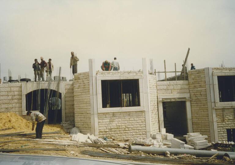 A building site has building men standing on the top of a building.