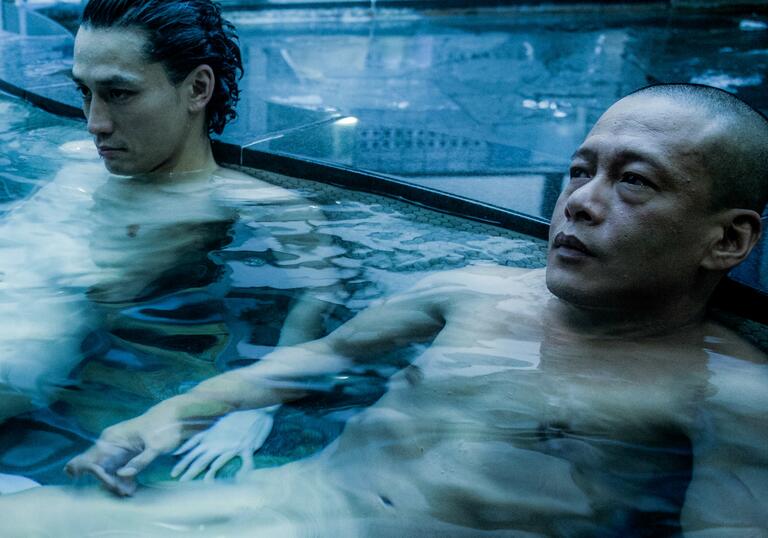 Two men bathe in a night pool.