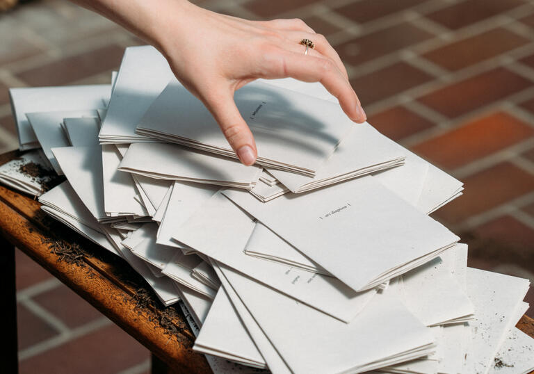 Hand grabbing pile of poetry books on table