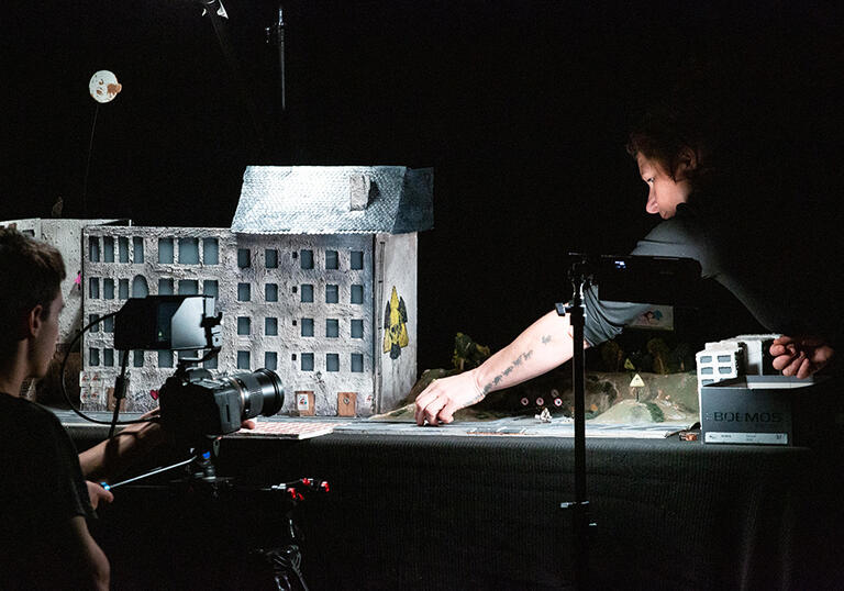 people filming a miniature set