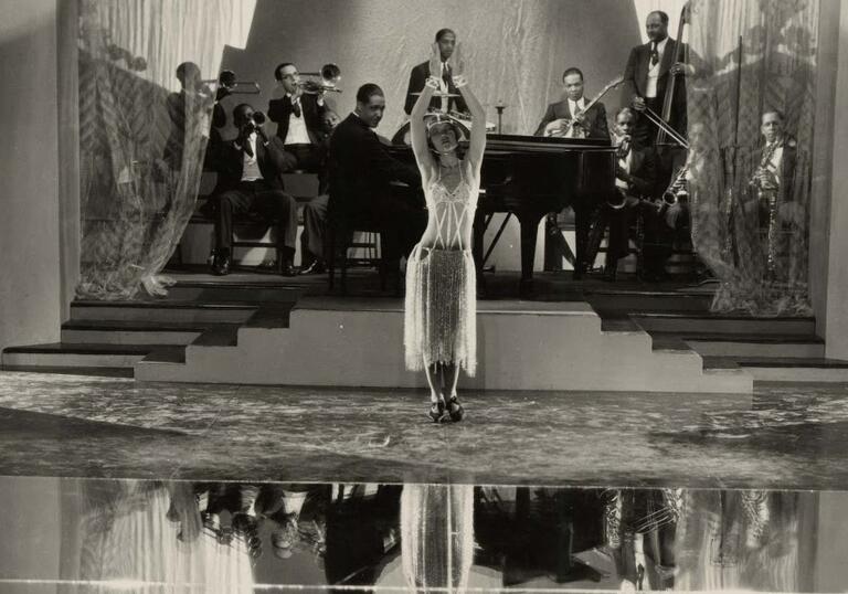 A woman dances on a stage in front of a jazz band.