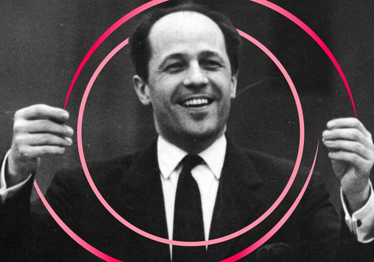 Black and white photo of Boulez with his hands raised in front of him. There are pink circular swirls around him.