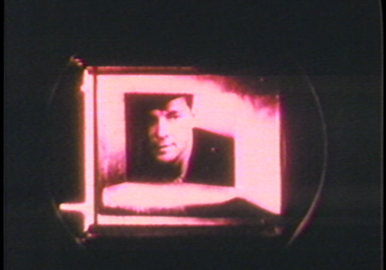 A pink image of a man peering through a box. 