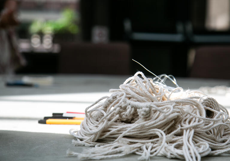 A pile of string and a set of pens side-by-side on the floor. 