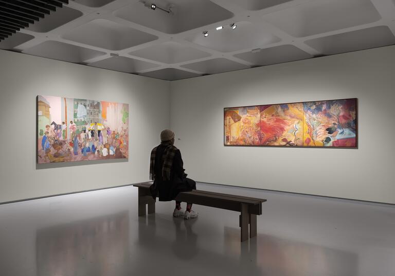 a person sits on a bench in front of two paintings