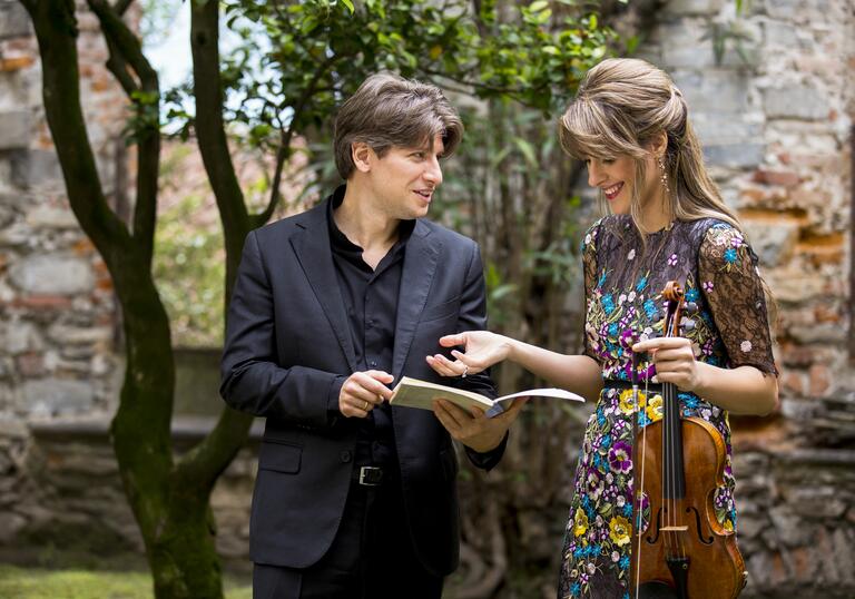 Conductor Daniele Rustinoi and violinist Francesca Dego chatting in a park