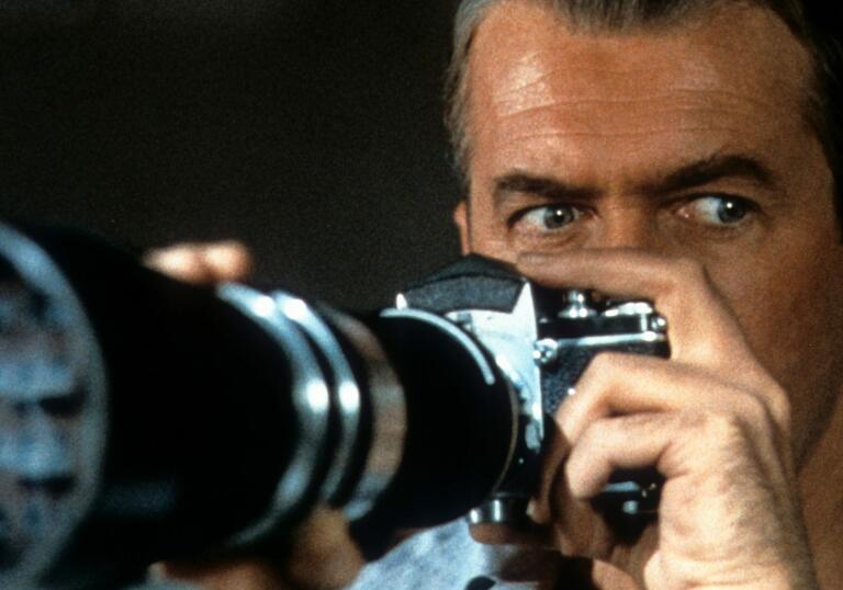 A man looks over the top of a long lens camera.