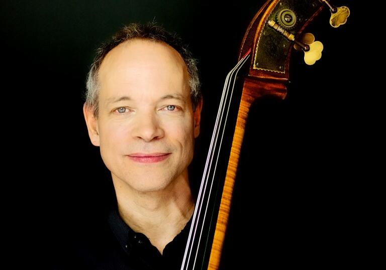 Alec Dankworth holding double bass against black background