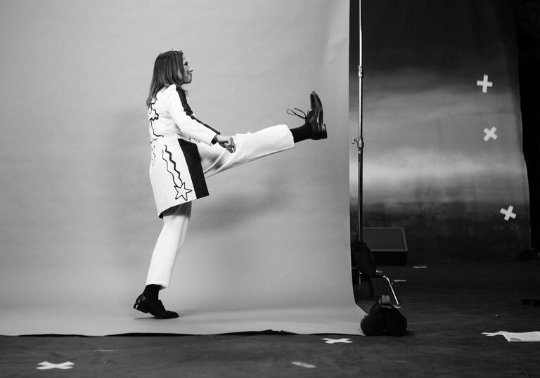 Profile of Kim Deal kicking leg up, in photo studio