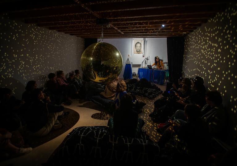 A group of people gather in a room to watch a music performance. 