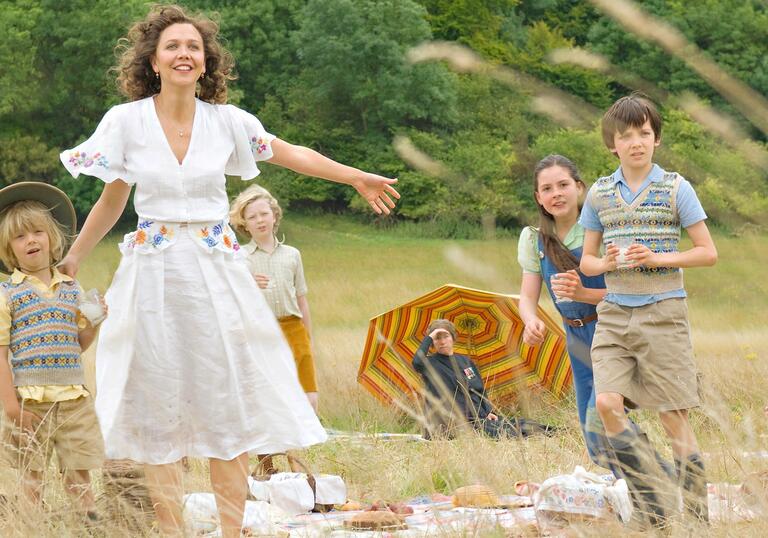 A woman and her children play in a field.