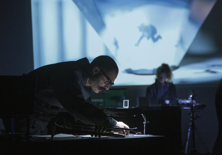 An image of a person bent over a table inspecting a trumpet