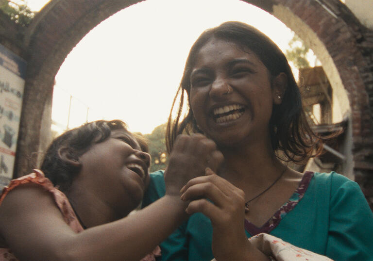 Two women laugh and hold hands.