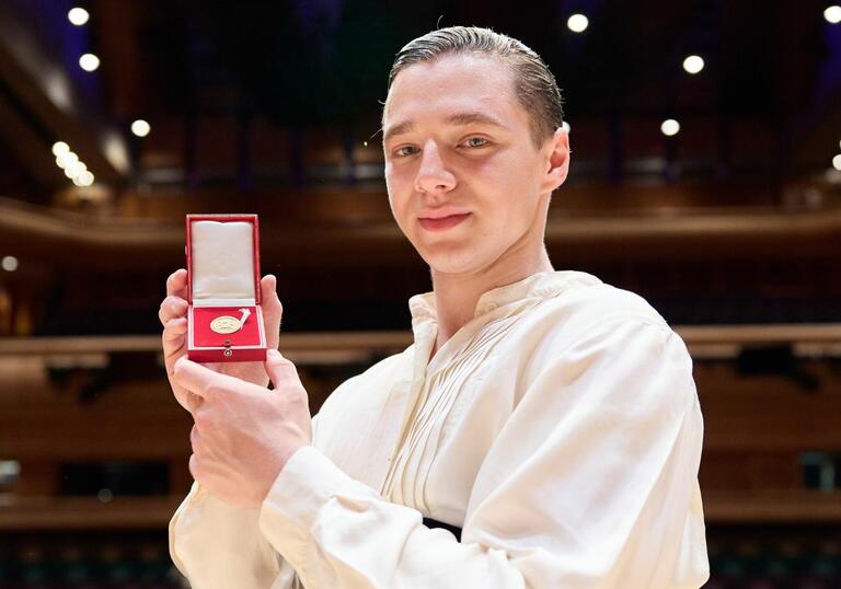 Double Bassist Strahinja Mitrović pictured in Barbican Hall, holding up the Gold Medal in box