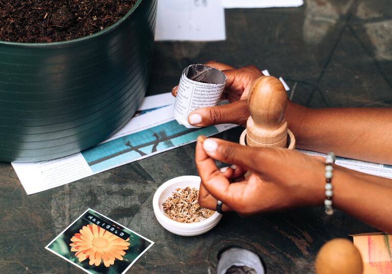 A close-up image of a pair of hands at a workshop, working with flowers and tea leaves.