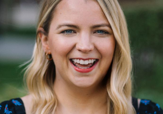 Katrina Bell headshot, she has shoulder length blonde hair a big smile and is wearing a blue floral top