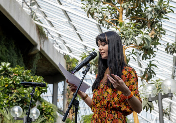 Rachel is standing in a conservatory in front of a microphone