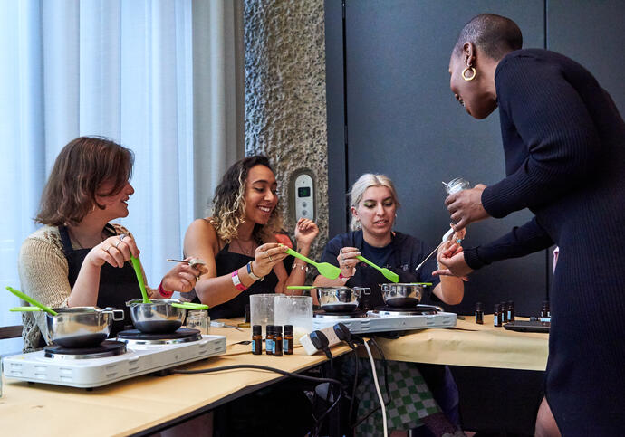 Image of 3 people being helped by 1 individual in candlemaking workshop