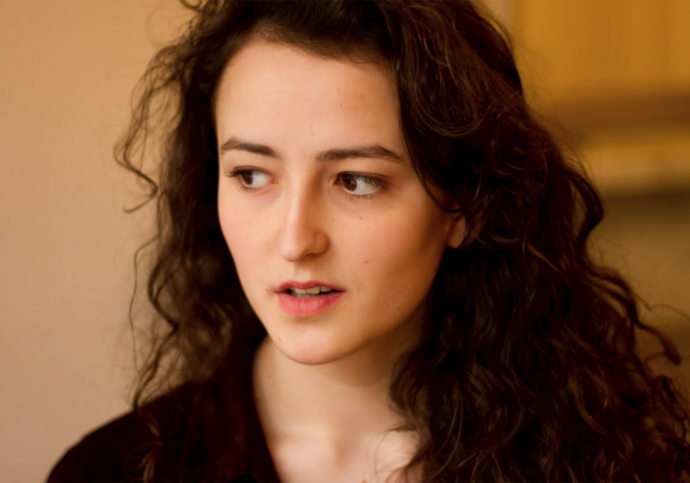 Person with long curly hair looking into distance