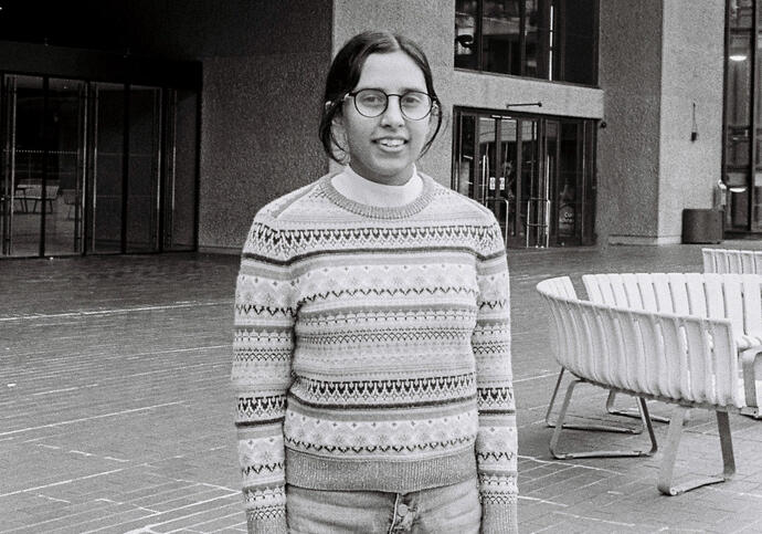 Person in patterned jumper and jeans standing in front of Barbican