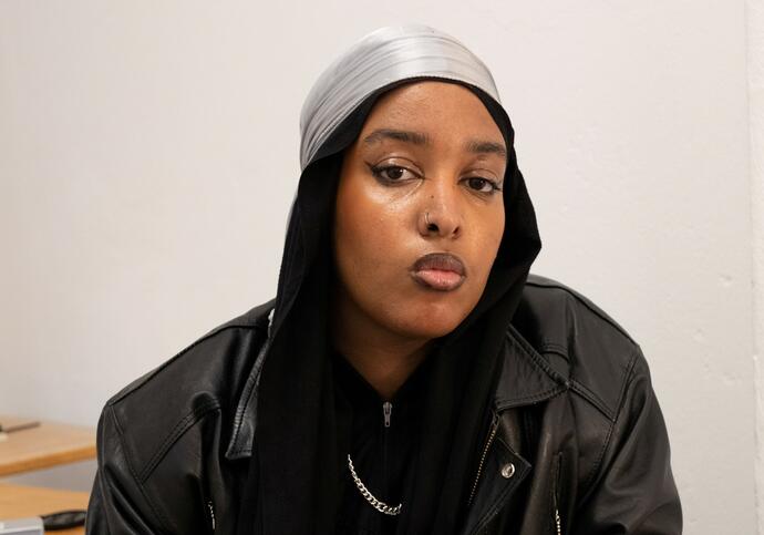 Person wearing leather jacket and black headscarf