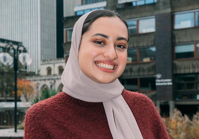 Girl wearing maroon jumper and beige headscarf