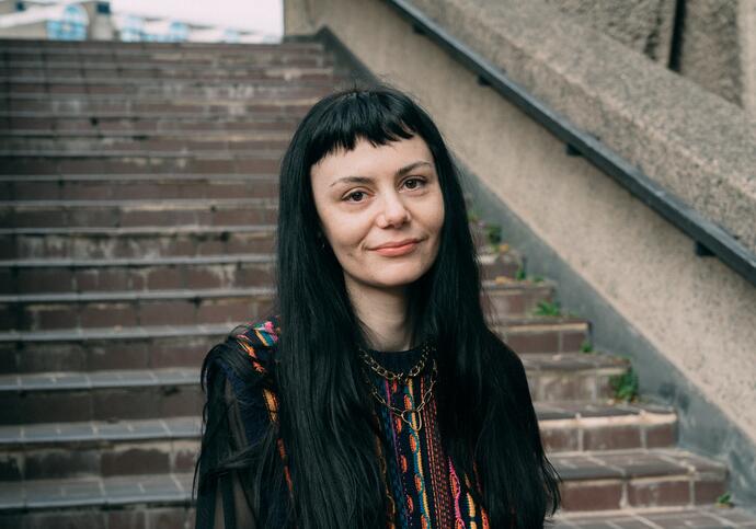 Person with long black hair standing on stairs