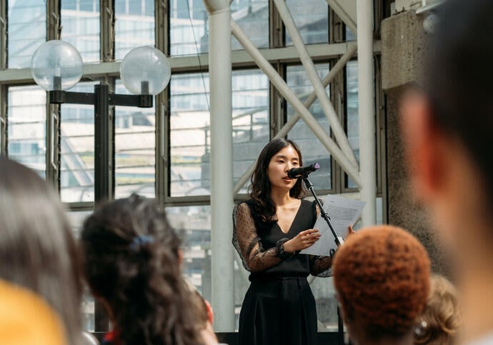performer wearing a black dress standing in front of a microphone inside the conservatory