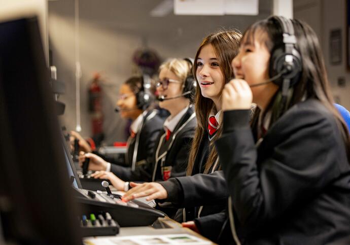 three girls wearing headphones looking at a computer at the Barbican Backstage experience