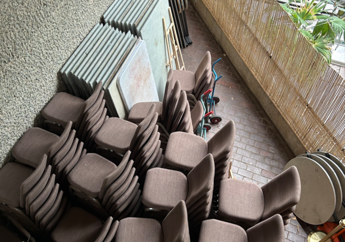 A pile of stacked chairs sit messily in a corner of the conservatory