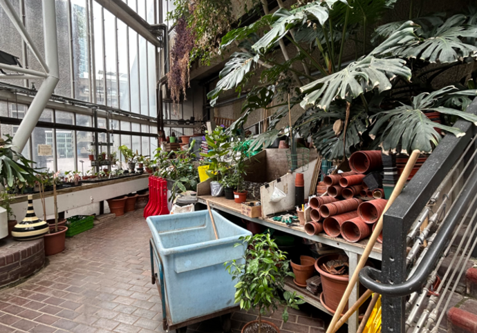 A blue trolley is left outside of a cluttered bench in the Conservatory