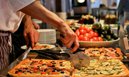 Photo of man cutting a slice of pizza