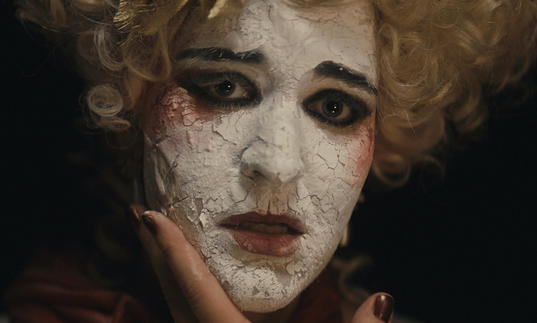 Actor in crumbling chalk white face paint