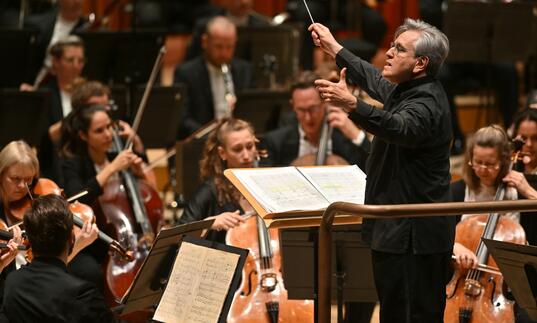 Sir Antonio Pappano conducting the LSO on the Barbican stage, with LSO cellos and violas in the background.