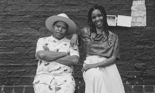 Siya and Thandi leaning against a brick wall