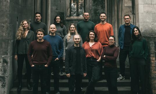 Sansara Choir standing on the steps of an old, abandoned church