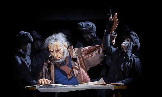 puppet grey-haired man reading, skeleton puppet in black cloak pulling the man's arm back