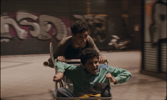 Two people play in the street with a cart