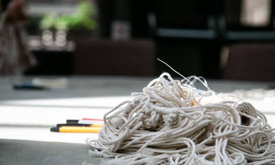 A pile of string and a set of pens side-by-side on the floor. 