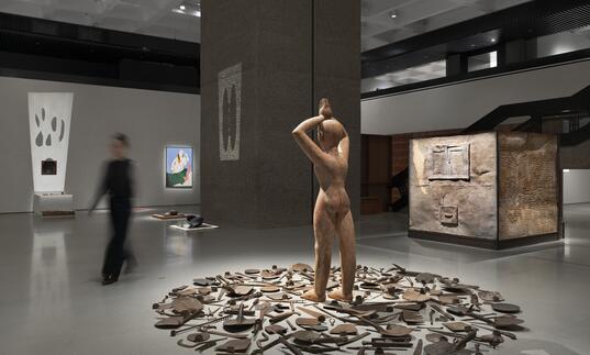 sculpture of a man surrounded by tools, in a gallery