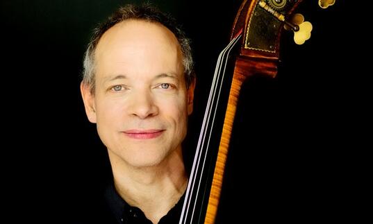 Alec Dankworth holding double bass against black background