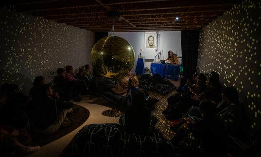 A group of people gather in a room to watch a music performance. 