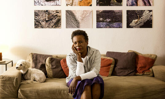 Claudia Rankine sitting on a sofa, resting her head in her hand.