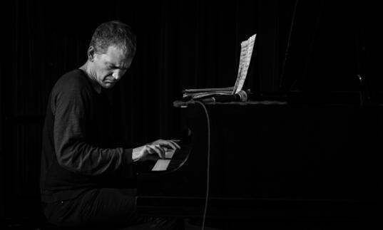 A black and white photo of pianist Brad Mehldau playing the piano