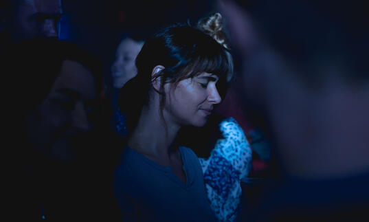 Joana Santos stands in a crowd, covered in blue light